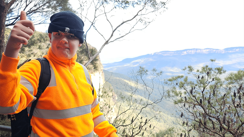 A young boy posing for a photo in front of a scenic view in the blue mountains